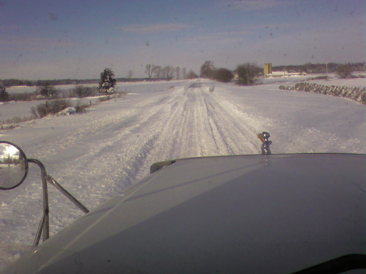 View from transport truck of a road covered in snow.