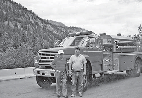 2 men stand in front of a new tanker truck.
