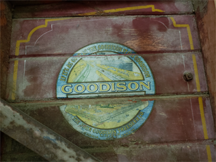 Close up of the side of the Goodison Thresher showing a stamp with an illustration of the factory and reads "If it's as good as the Goodison it is a Goodison GOODISON The John Goodison Thresher Co. Limited Sarnia, ONT. Canada."