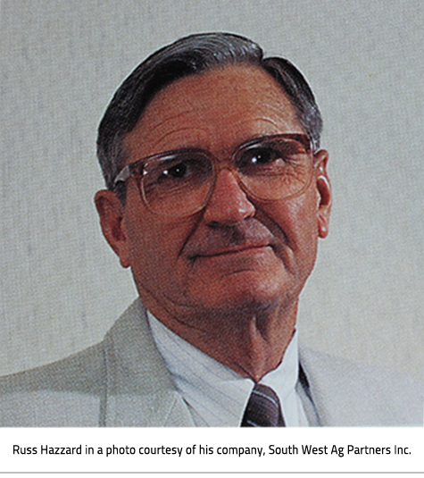 Man with dark hair and large rimmed glasses, dressed in a suit. Image Caption: : Russ Hazzard in a photo courtesy of his company, South West Ag Partners Inc.