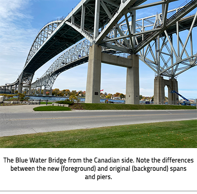 (The two Blue Water Bridges from below, spanning over a road and then the St.Clair River. The new bridge has an arch. Image Caption: "The Blue Water Bridge from the Canadian side. Note the differences between the new (foreground) and original (background) spans and piers."), link.
