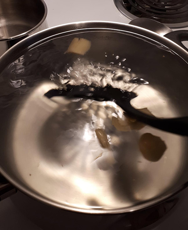 Spoon stirring water in a pot.