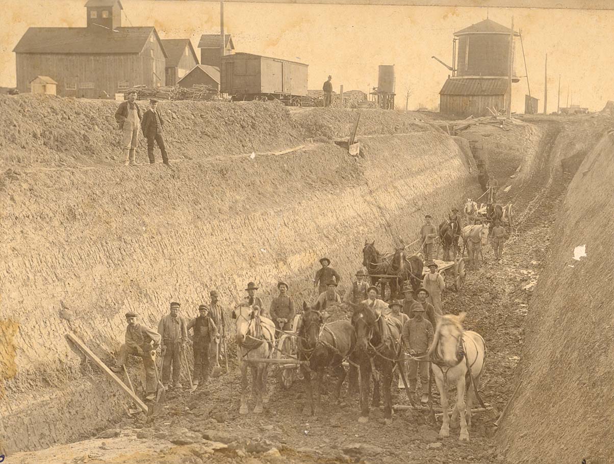 Horses, wagons, and men digging a path.