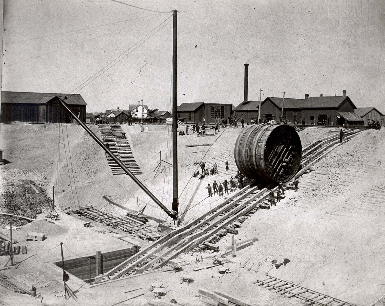 Cylindrical item rolling down wooden tracks on a hill.