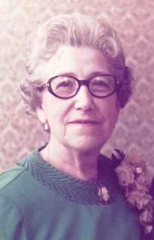 portrait of a woman with grey hair, glasses and a green top