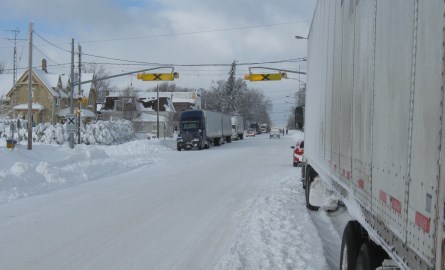 Street of Wyoming, Ontario in a snow storm with transport trucks.