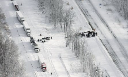 Ariel view of a highway stopped in a snowstorm with emergency services.