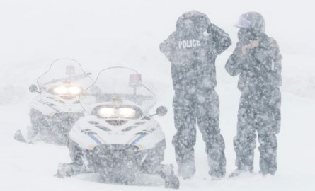Two policeman with snowmobiles.