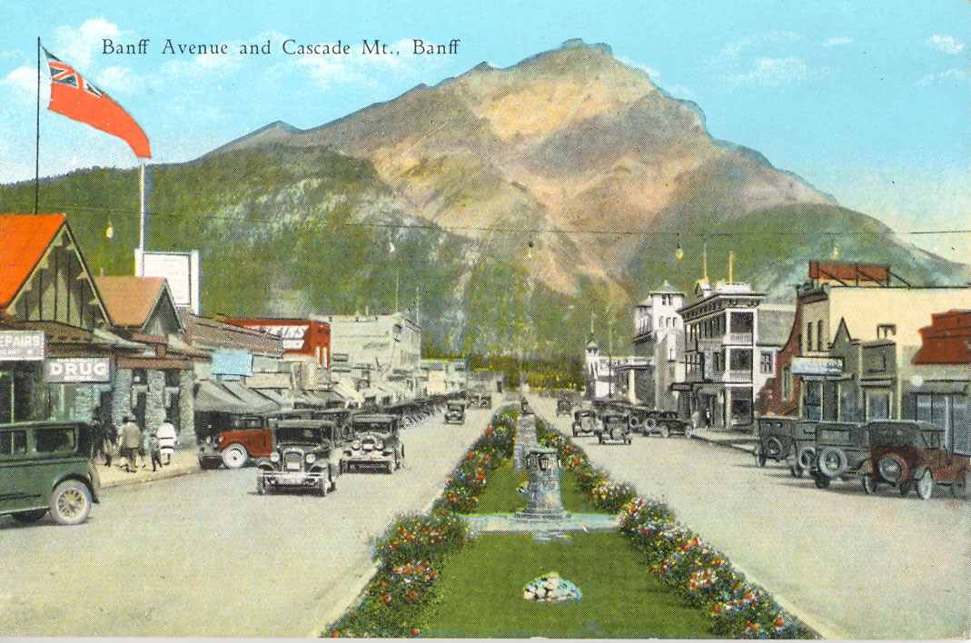 Old cars parked in front of tents and a mountain.