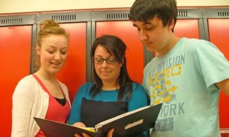 Women standing in front of lockers with two students beside her.