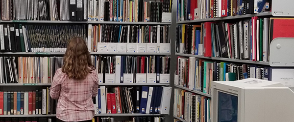 Woman standing in front of book shelving at the Archives.