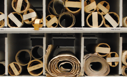 An image of rolls of parchment and stacks of aged ledgers.