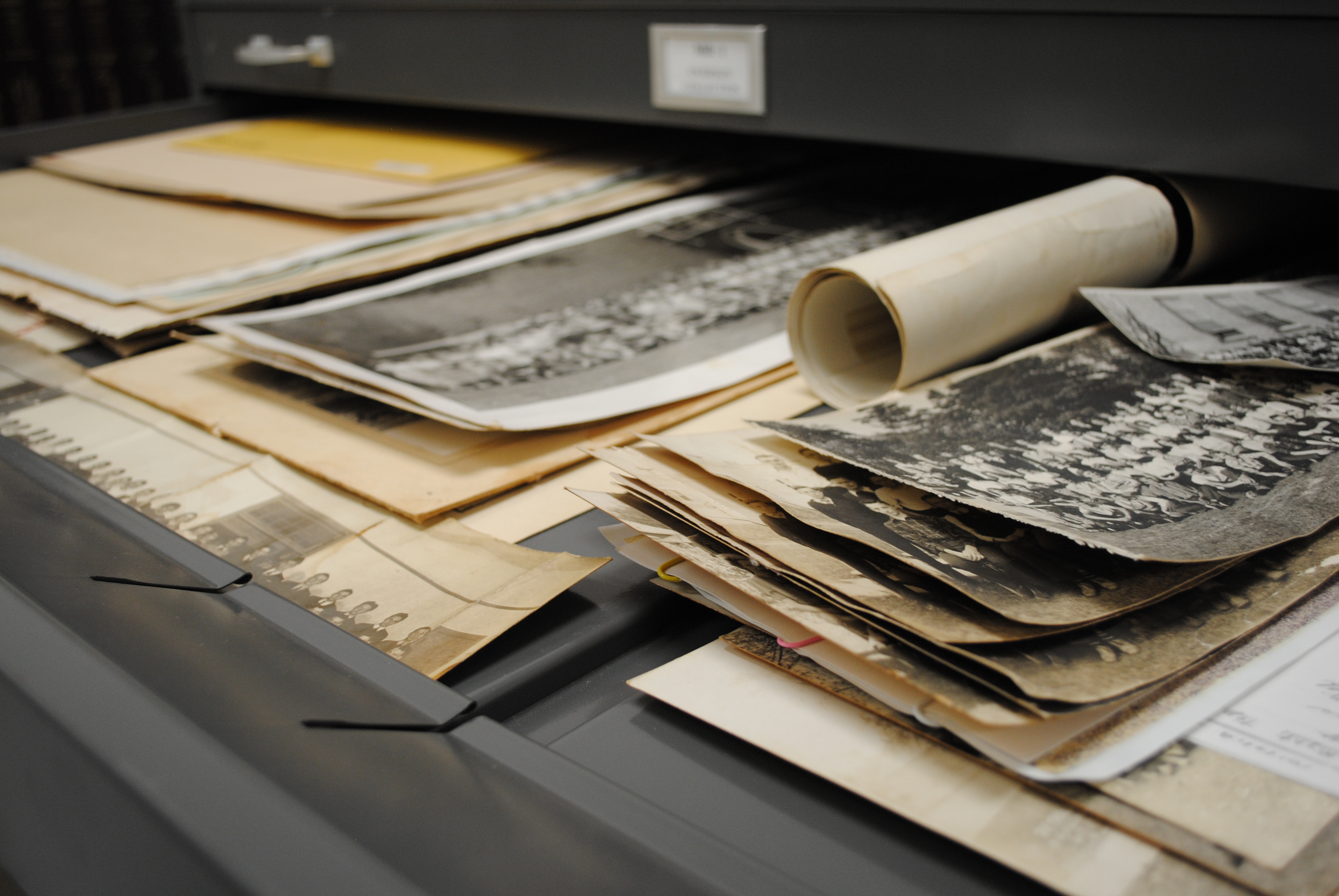 Photos and rolled papers in a filing drawer.