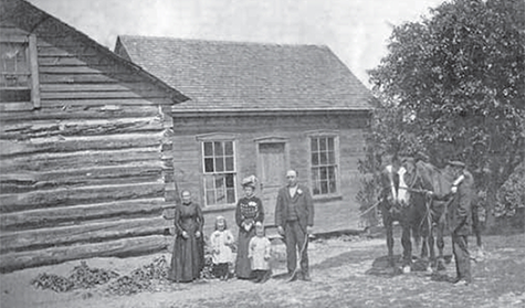 Settler's log cabin with a family standing outside.