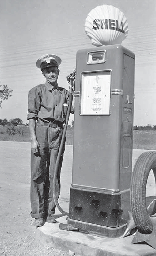 Norman Wilson standing beside a shell gas pump.