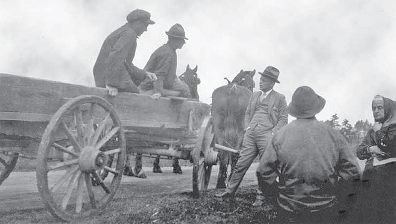 People on a wagon talking to people on the side of the road.