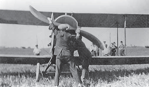 Man turning the propeller of an Old Jenny airplane.