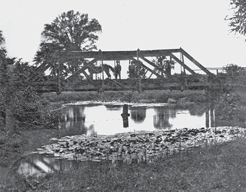 Horse and buggy crossing a truss bridge.
