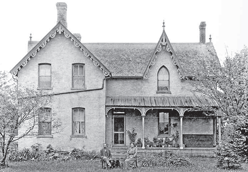 A large two story house with a couple sitting out front.