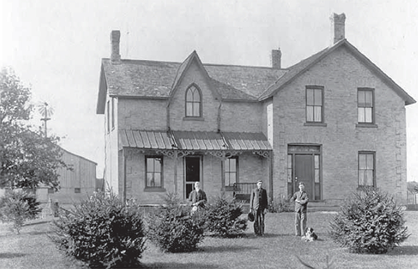 Brodie homestead: A large brick home, three men stand outside.