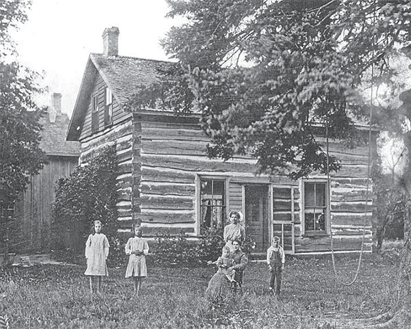 Benedict family in front of a log home.