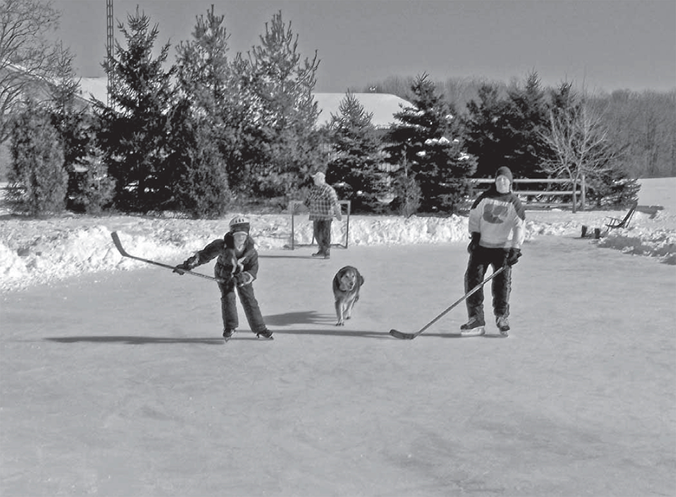 Durr family playing hockey in field west of house.