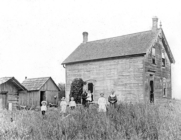 Higgins family in front of their wood home.