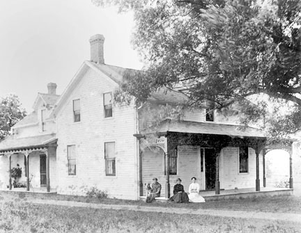 McAdam family sitting on the veranda of a large house.