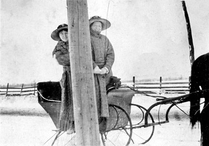 Irene and Jean Williamson peeking around a telephone pole.