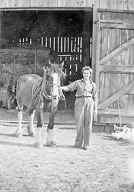 Lottie Davidson leading a horse out of a barn.