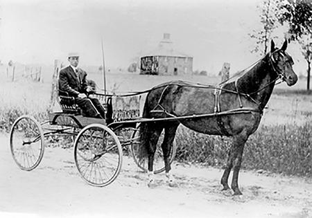 Roy Hollingsworth in a wagon pulled by one horse.