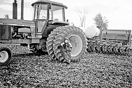 Brad Savoie beside John Deere tractor with planter.