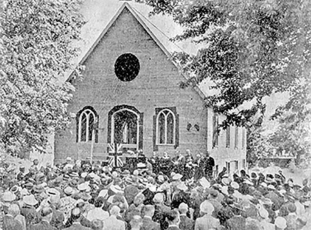 A crowd of people stand in front of the United Church at its opening ceremony.