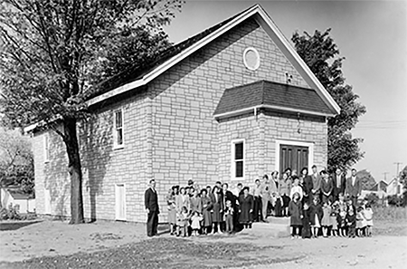 Arkona Pentecostal Church with a group of people in front.