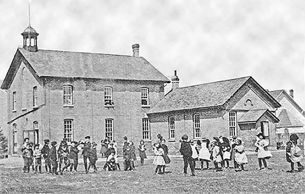 Arkona Public School with children outside playing in the yard, 1907.