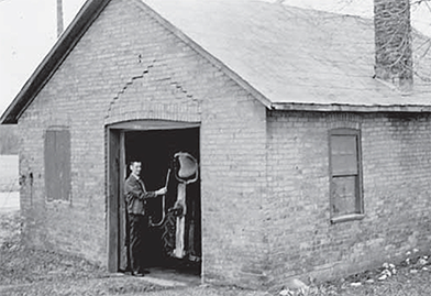 Blacksmith shop with Roy Cable standing in doorway.