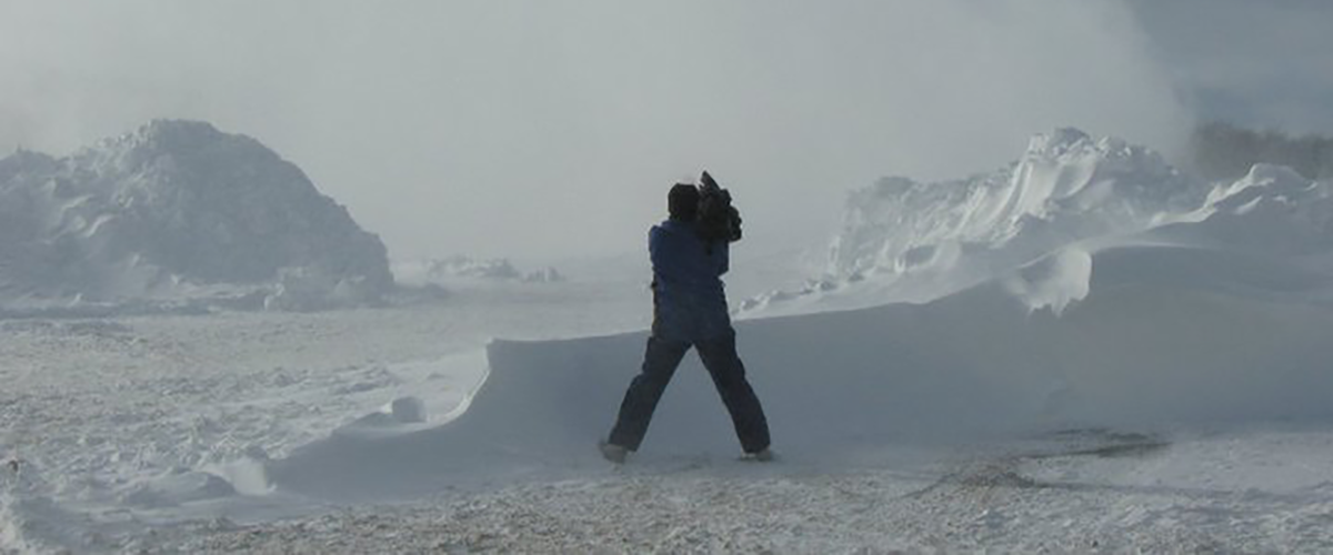 Man standing in the snow with a camera.