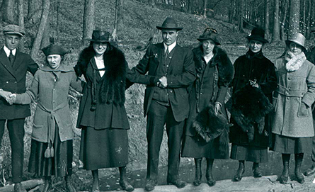 Black and white photo of a group of people standing outdoors in formal winter-wear.