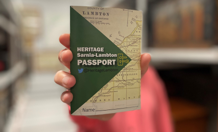 Hand holding up a Heritage Sarnia-Lambton passport.