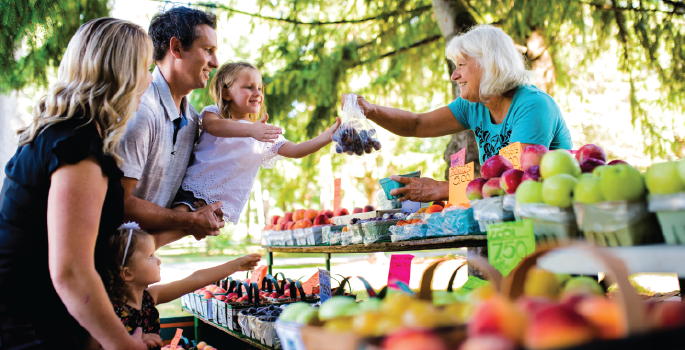 family purchasing fruit at an outdoor market