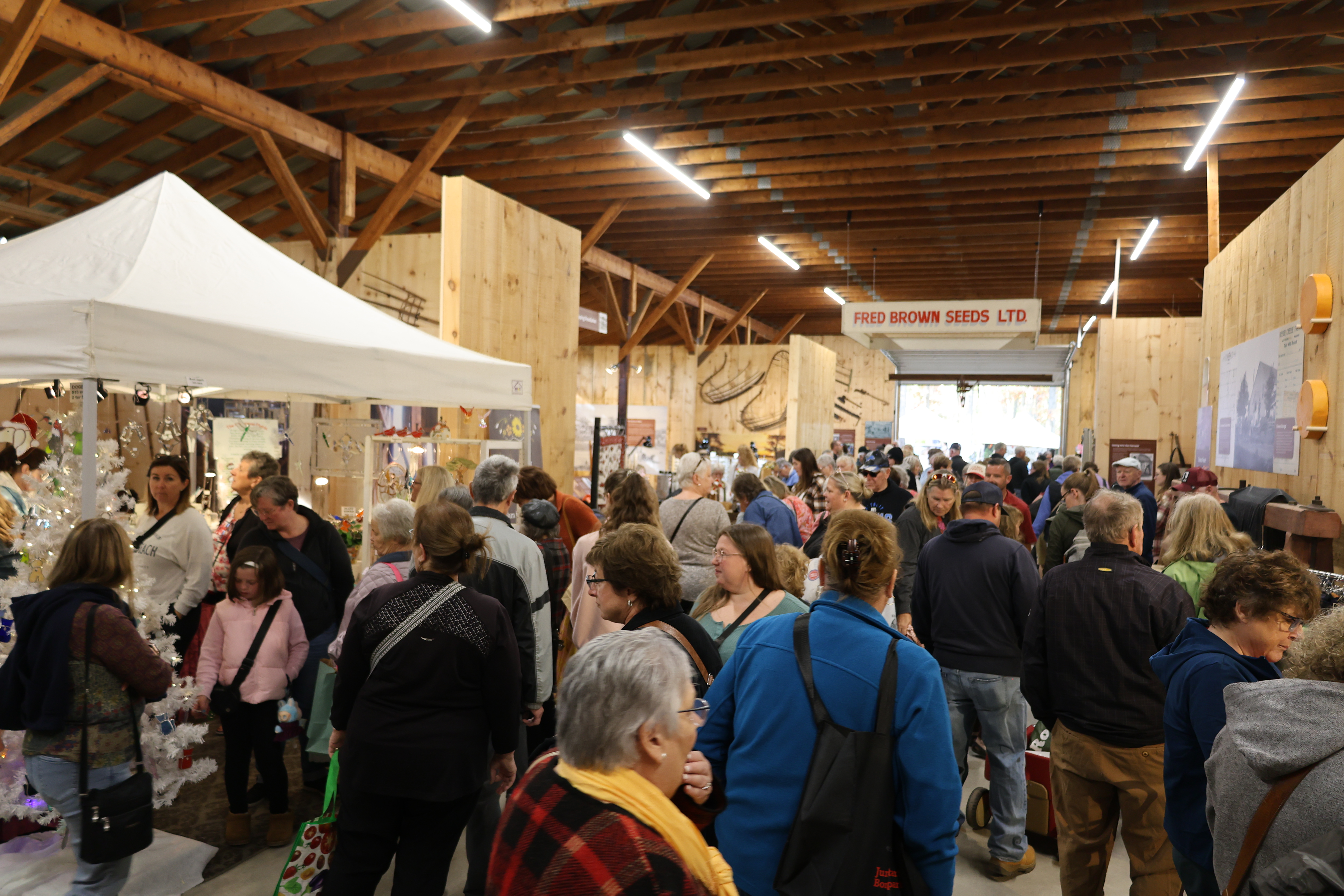 Crowd surrounding vendors in the Agricultural Barn at Lambton Heritage Museum.