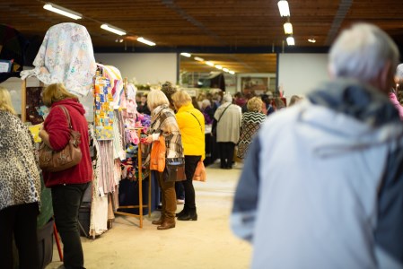 Crowd in a building with tables with vendors.