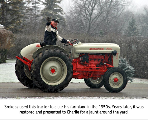 Charlie Srokosz waving from his tractor in the rain. Image Caption: "Srokosz used this tractor to clear his farmland in the 1950s. Years later, it was restored and presented to Charlie for a jaunt around the yard."