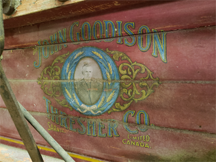 Close up of the side of the Goodison Thresher with a picture of John Goodison. Text around the image reads "John Goodison Thresher Co. Limited Sarnia Canada"