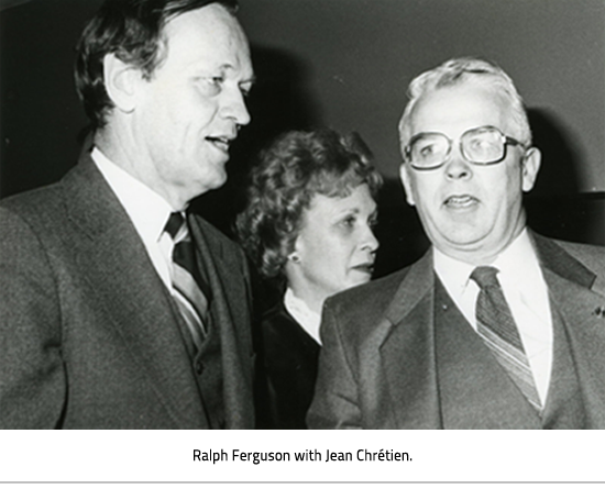 Ralph Ferguson talking with Jean Chrétien with a woman in the background. Image Caption: Ralph Ferguson with Jean Chrétien.