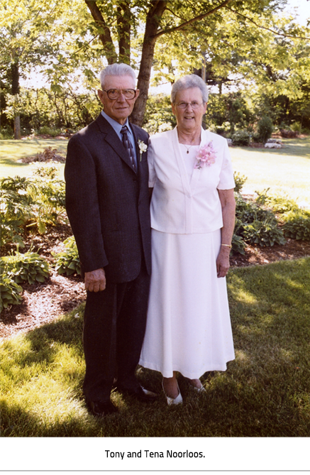 (Tony and Tena Noorloos all dressed up and posing for a picture in front of a garden in someone's front yard. Image Caption: "Tony and Tena Noorloos"), link.
