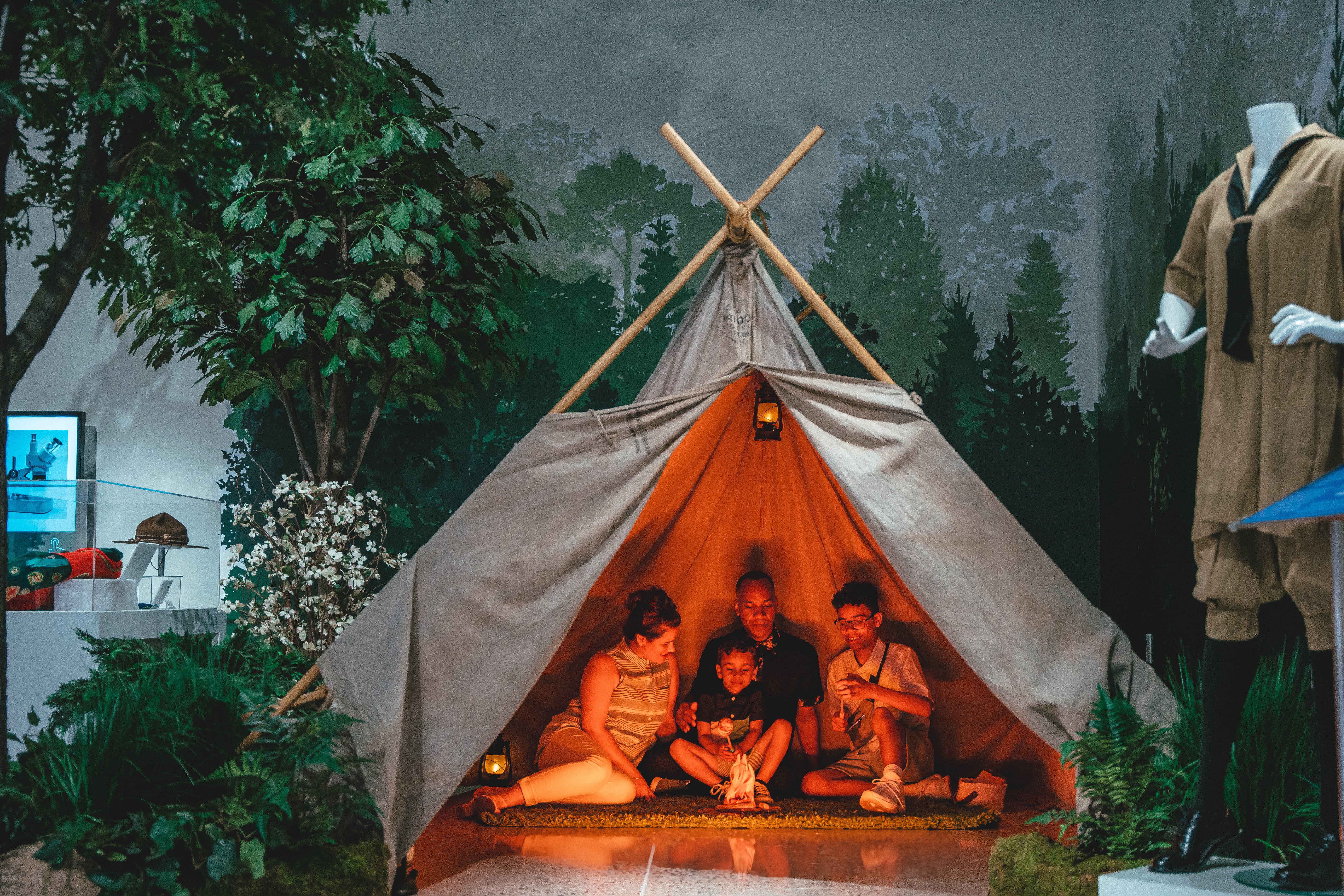 Family in a tent and girl scout uniform on display