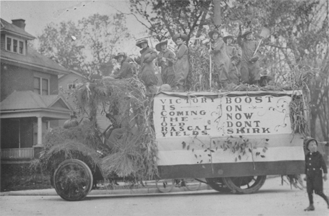 Photo of women dressed in farm work clothing on a float in a parade, link.
