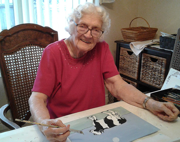 Elder lady painting a cow.