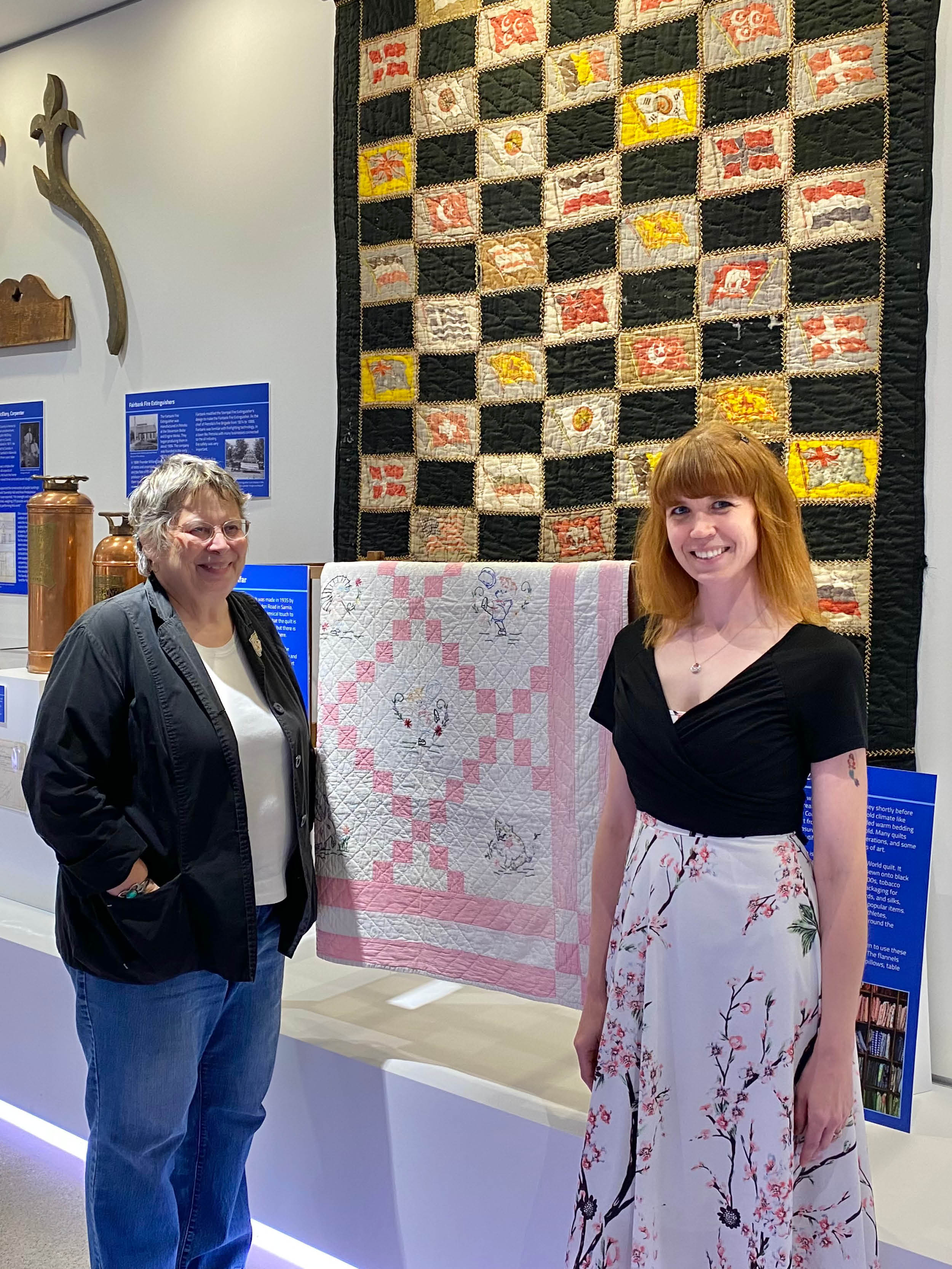Susan and Dana in front of a quilt on display at the museum